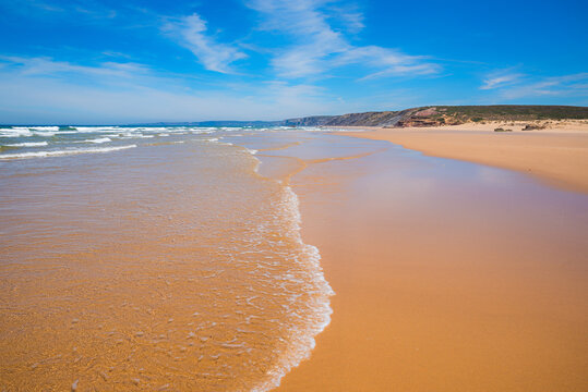 Stunning coastal landscape with waves washing onto the beach. Space for text on the sand
