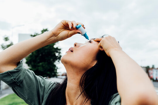 Young woman putting drop in eye