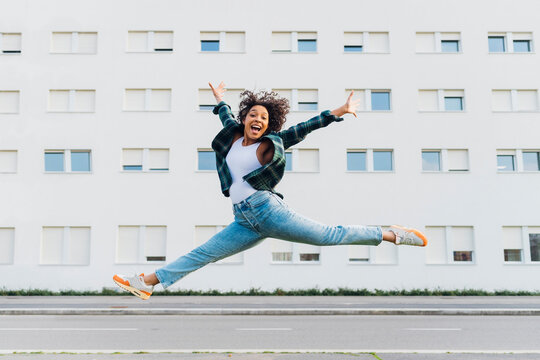Cheerful woman jumping in front of building