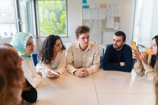 Students having discussion sitting around table in classroom