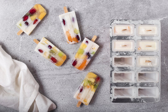 Homemade fruits and yogurt ice lollies on marble
