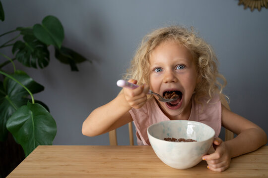 Blond girl eating breakfast at home