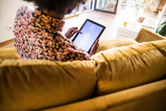 Woman using smart home app on digital tablet in living room
