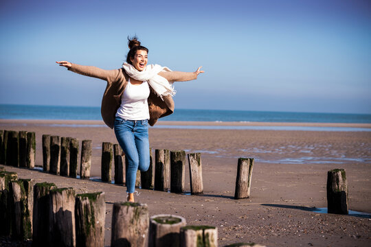 Tourist jumps on beach breakwaters during a sunny holiday