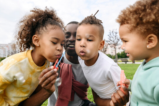 Children blowing bubble with father in park