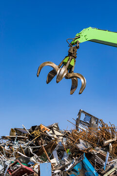 Germany, Baden-Wurttemberg, Stuttgart, Mechanical claw over heap of scrap metal lying in junkyard