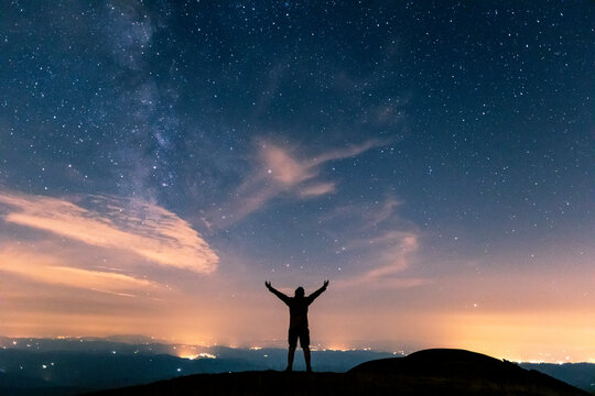 Italy, Monte Nerone, silhouette of a man looking at night sky with stars and milky way