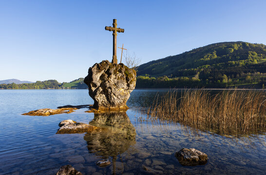 Wooden cross on a large rock in a calm lake
