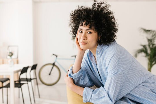 Smiling young woman with head in hand at home