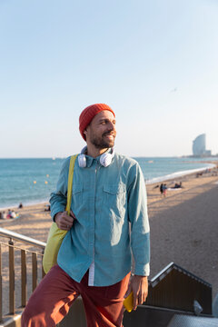 Smiling tourist with tote bag on stairs at Barcelona beach