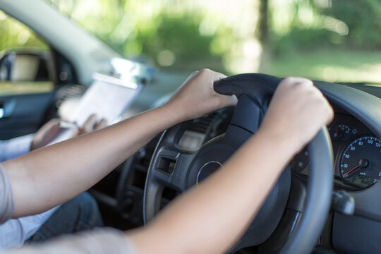 Hands of teenage girl at car steering wheel