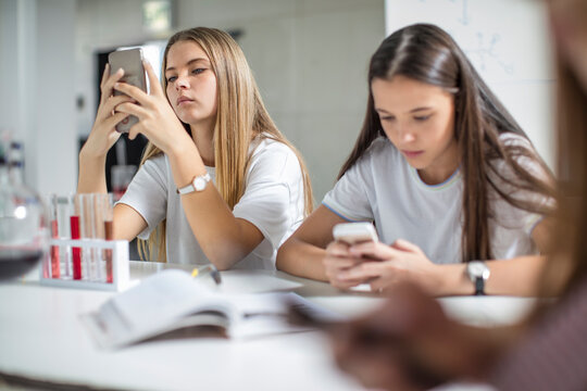 Teenage girls using cell phones in science class