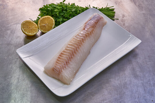 Cod fillet on a white plate with parsley and lemon