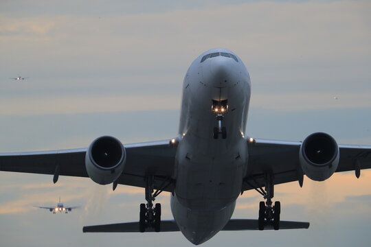 A commercial airliner climbing after takeoff at dusk.
