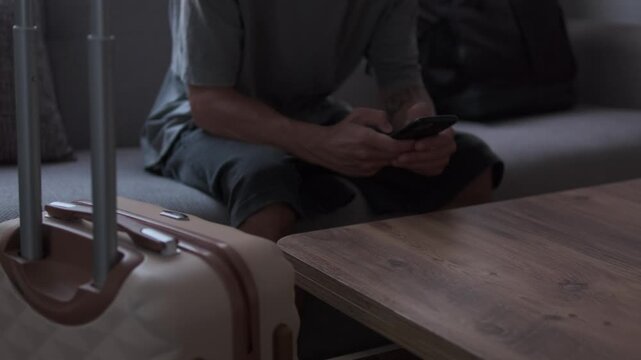 Checking phone while waiting for departure in temporary accommodation, travel uncertainty and life between moves concept
