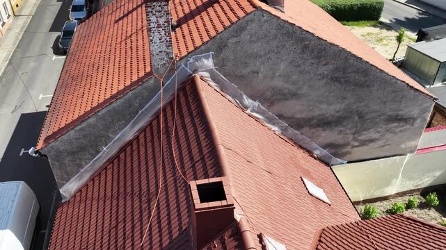 Roof renovation process with spray painting of roof tiles, including priming and applying second coat of paint on a residential roof, showing professional exterior maintenance and refurbishment work.