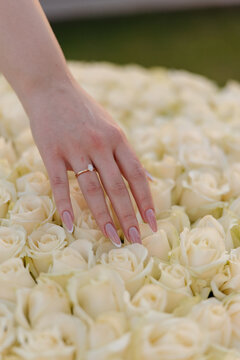 Woman hand with diamond engagement ring on white roses bouquet