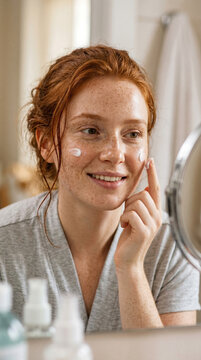 Morning skincare routine featuring young red-haired woman with freckles applying cream to face skin beauty home healthy glowing skin relaxing spa mood self care beauty ritual natural