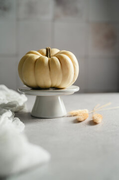 White ornamental pumpkin on cake stand, minimalist autumn still life