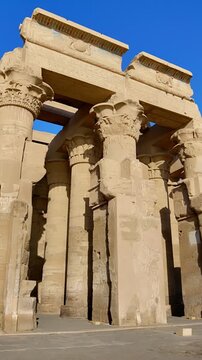 Kom Ombo temple ruins with double columns and composite capitals against clear blue sky in Egypt, ancient Ptolemaic architecture dedicated to Sobek and Horus with damaged walls