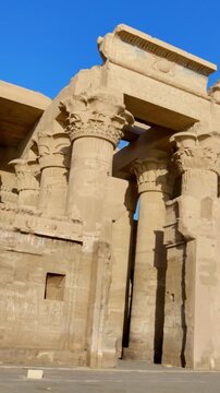 Kom Ombo temple ruins with double columns and composite capitals against clear blue sky in Egypt, ancient Ptolemaic architecture dedicated to Sobek and Horus with damaged walls
