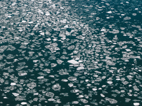 Aerial view of scattered ice floes drifting on the dark blue ocean surface near Unalaska, Alaska, United States.