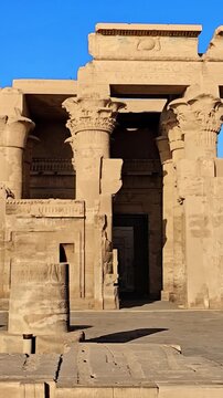 Kom Ombo temple ruins with double columns and composite capitals against clear blue sky in Egypt, ancient Ptolemaic architecture dedicated to Sobek and Horus with damaged walls