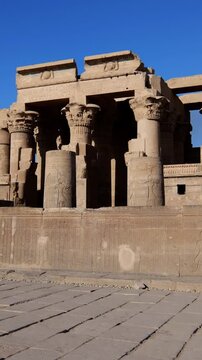 Kom Ombo temple ruins with double columns and composite capitals against clear blue sky in Egypt, ancient Ptolemaic architecture dedicated to Sobek and Horus with damaged walls