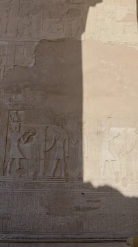 Kom Ombo temple columns with composite capitals and hieroglyphic carvings viewed from below against blue sky in Egypt, upward perspective of ancient sandstone architecture