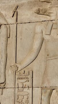 Kom Ombo temple columns with composite capitals and hieroglyphic carvings viewed from below against blue sky in Egypt, upward perspective of ancient sandstone architecture