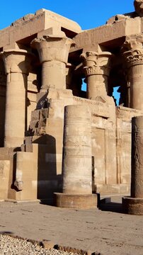 Kom Ombo temple ruins with double columns and composite capitals against clear blue sky in Egypt, ancient Ptolemaic architecture dedicated to Sobek and Horus with damaged walls