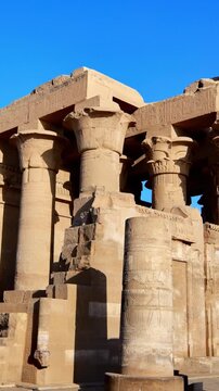 Kom Ombo temple ruins with double columns and composite capitals against clear blue sky in Egypt, ancient Ptolemaic architecture dedicated to Sobek and Horus with damaged walls