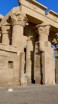 Kom Ombo temple ruins with double columns and composite capitals against clear blue sky in Egypt, ancient Ptolemaic architecture dedicated to Sobek and Horus with damaged walls