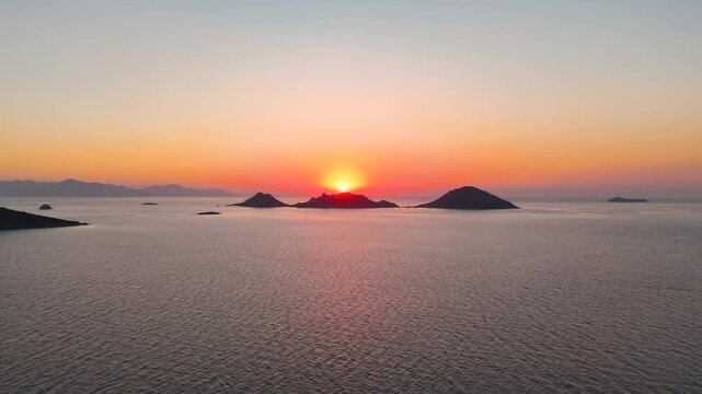 Cinematic aerial drone rising reveal shot over Aegean Sea at sunset with Kadin Adalari islands silhouette during golden hour magic hour Bodrum Turgutreis peninsula Mugla Turkey