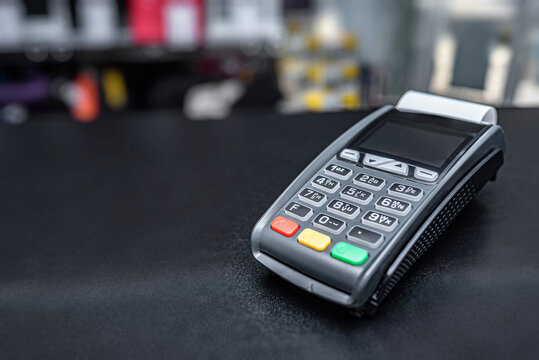A modern credit card terminal sits on a black counter in a retail store.
