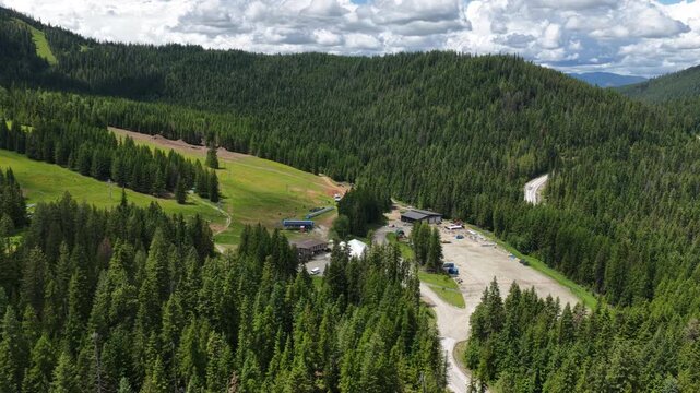 Aerial of ski resort village and forest in Stevens County Washington with cleared slopes for recreation and visible chair lift  in summer