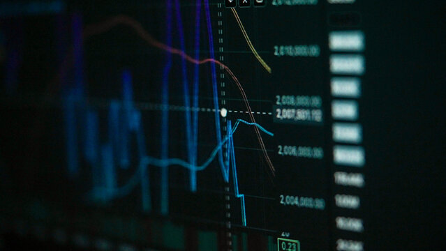 Dark screen glows with financial charts and lines. Blue and red curves track stock prices. Numbers scroll down in quiet precision. No people, just data's cold, steady pulse. Perfect for business