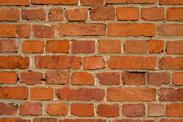 Fototapeta premium Red brick wall texture with uneven surface and mortar joints, ideal for backgrounds and design