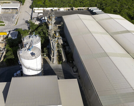 Aerial view of Ergon Asfaltos Progreso industrial facility featuring large storage silos, processing equipment, and warehouse buildings in Progreso, Yucatan, Mexico.