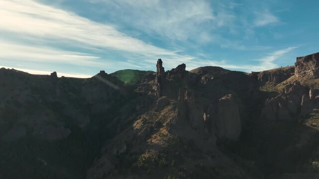 Aerial view of El Dedo de Dios rock formation, a prominent vertical spire rising from the rugged, volcanic mountainsides of Valle Encantado, Patagonia, Argentina.