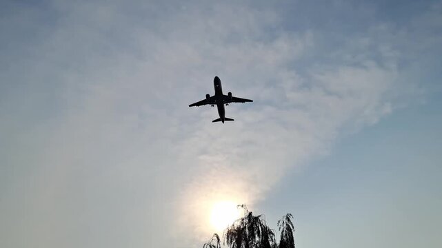 A tracking wide shot of a commercial passenger airplane flying high across a vast clear blue sky during daytime.