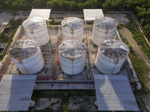 Aerial view of Petroservicios Yucatan storage tanks with white cylindrical containers, metal piping, and corrugated roofs in Progreso, Yucatan, Mexico.