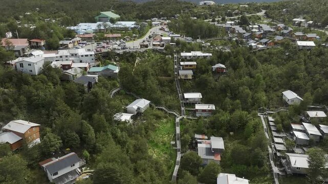 Aerial view of the remote coastal village of Caleta Tortel, highlighting the characteristic wooden staircases and pathways connecting houses nestled in the forest of Patagonia, Chile.
