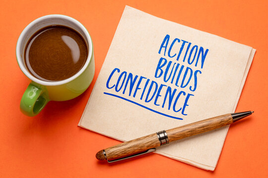 Action Builds Confidence &ndash; inspirational handwritten note on a napkin with coffee and pen, symbolizing courage, self-belief, and personal development.