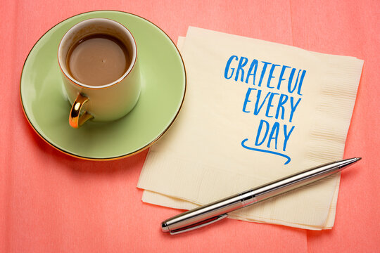 Grateful Every Day. Inspirational handwritten note on a napkin with coffee and pen, encouraging gratitude, mindfulness, happiness, and a positive mindset.