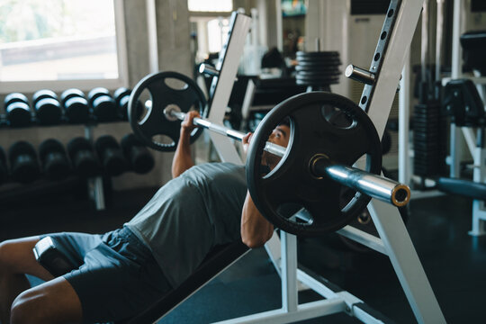 Barbell bench gym man weight exercise strength fitness muscle workout, man lifting barbell bench press gym with weight equipment, strength training, focused expression, athletic fitness routine