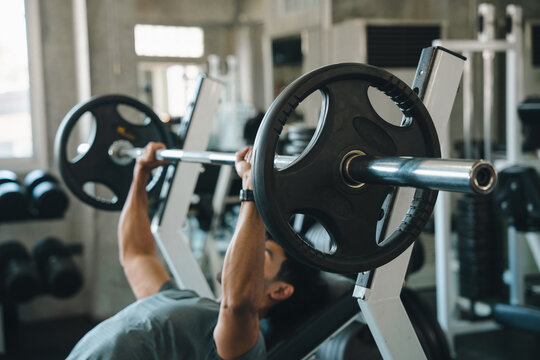 Barbell weight gym exercise bench press fitness strength workout athlete training male athlete lifting barbell during bench press exercise in indoor gym with weight equipment and focused effort