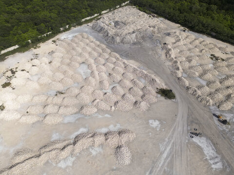 Aerial view of a lime processing facility with numerous piles of white limestone and dirt roads in Merida, Yucatan, Mexico.