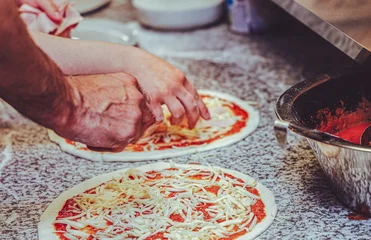 Fotobehang Pizzeria Restaurant kitchen staff preparing fresh pizzas by hand with tomato sauce and mozzarella cheese on a professional countertop. Authentic teamwork and real food preparation in a busy pizzeria.  © Samir