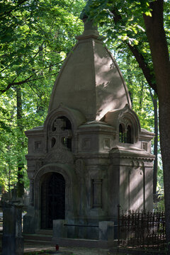 Ancient stone mausoleum crypt building stands inside a cemetery yard. This historical churchyard architecture represents family tomb burial, funeral mourning ritual and religious heritage.